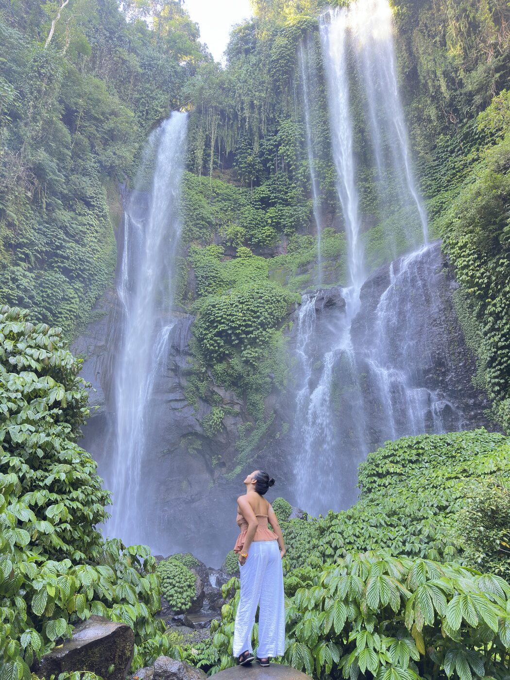 Standing beneath a jungle waterfall
